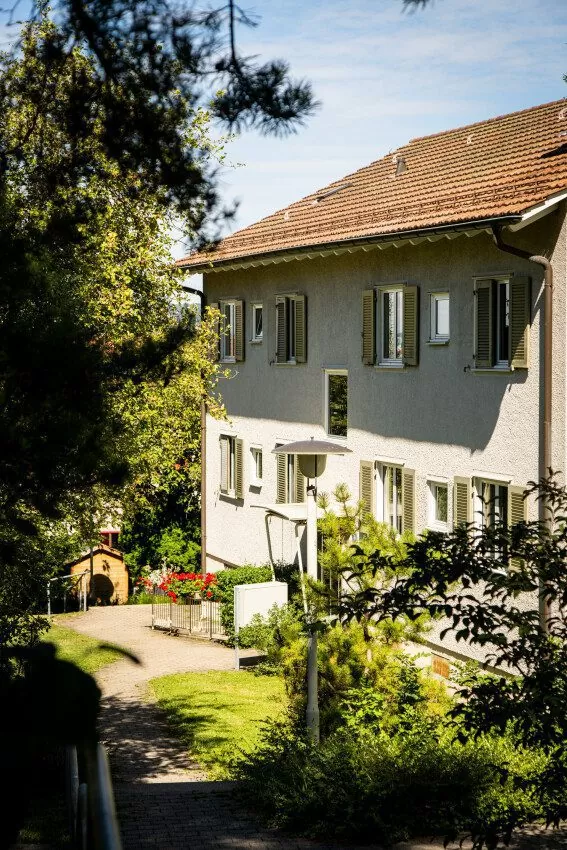 Fassade eines Mehrfamilienhauses mit Weg und Aussenraum in der FGZ-Siedlung Rossweidli (Etappe 18)
