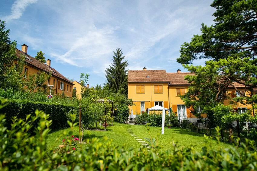 Reihen-Einfamilienhäuser aus der FGZ-Siedlung Staffelhof (Etappe 4) mit viel grünem Garten davor